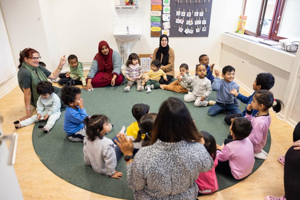 Barn och pedagoger i samling på golvet